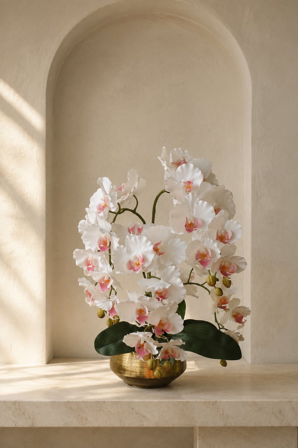 Four-stem ivory orchid arrangement in a brushed-gold bowl