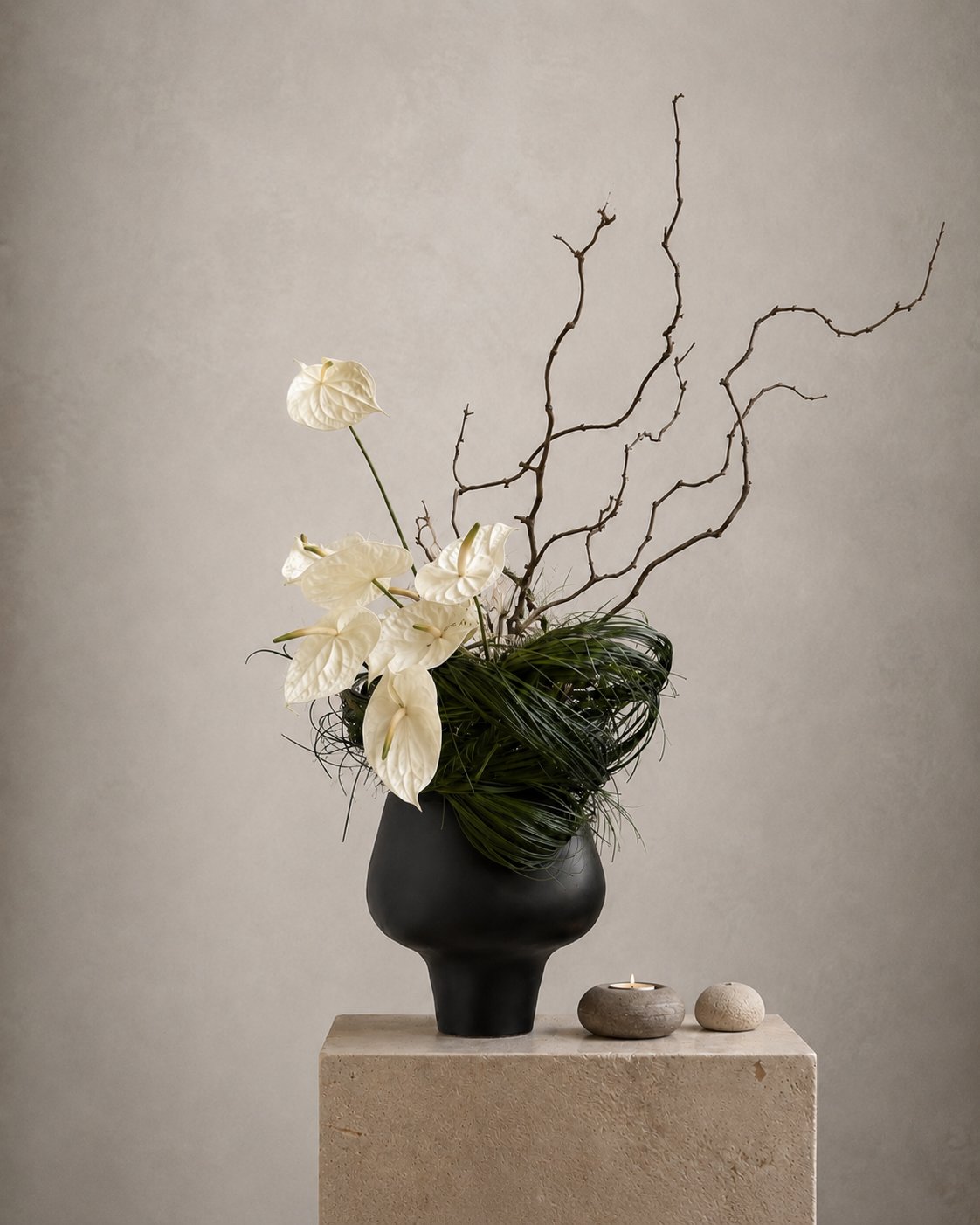Ivory anthurium and sculptural green arrangement in a black vase