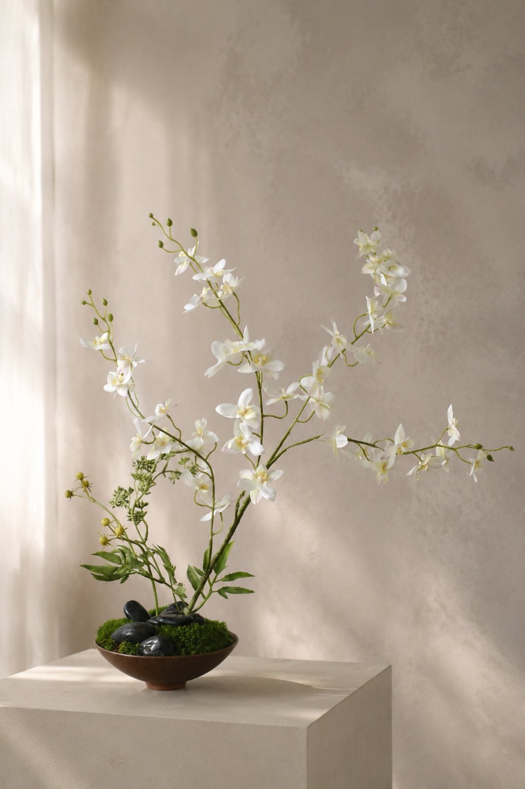 Airy white branch arrangement on a warm neutral pedestal